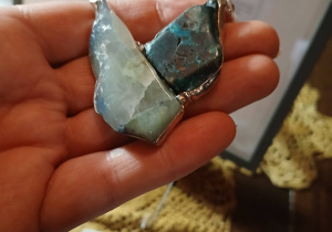 Dłoń trzymająca ozdobny kamień biżuteryjny w kształcie przypominającym motyla