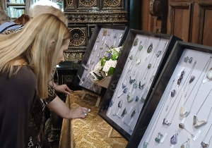 Osoba ogląda biżuterię prezentowaną w szklanych gablotach.