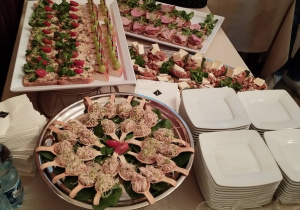 Stół cateringowy podczas spotkania, na nim różnorodne potrawy i napoje.