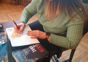 Autorka podpisuje swoją książkę dla czytelników biblioteki